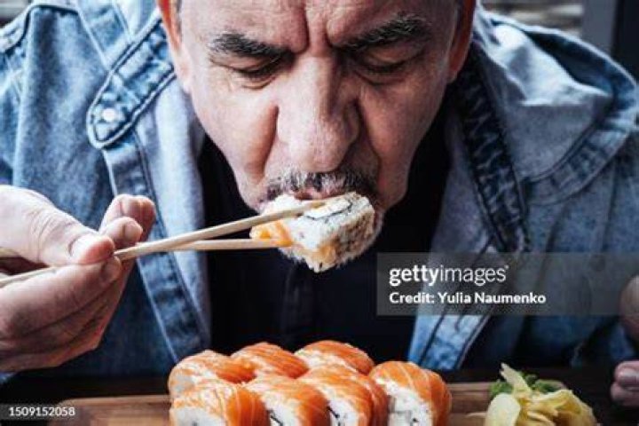 Adult man eating Japanese sushi rolls. Traditional Japanese food. adult man eating japanese sushi rolls traditional japanese food