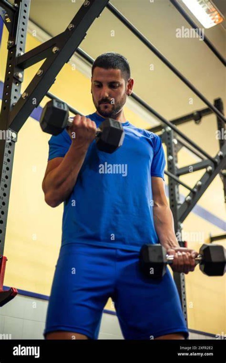 Athlete training with dumbbells in gym, screaming Athlete training with dumbbells in gym, screaming