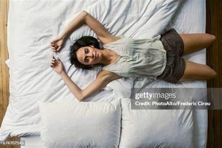 Beth lying on a bed with a notebook in a scene from The Walking Dead.
