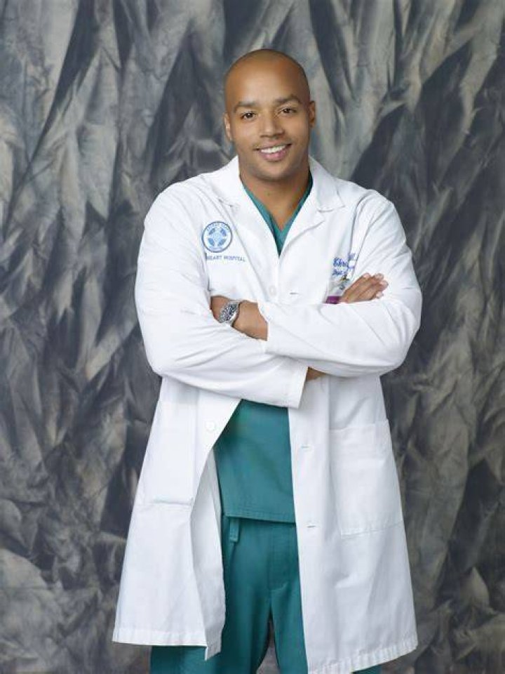 Christopher Turk and JD in Scrubs sitting side by side and smiling at each other.