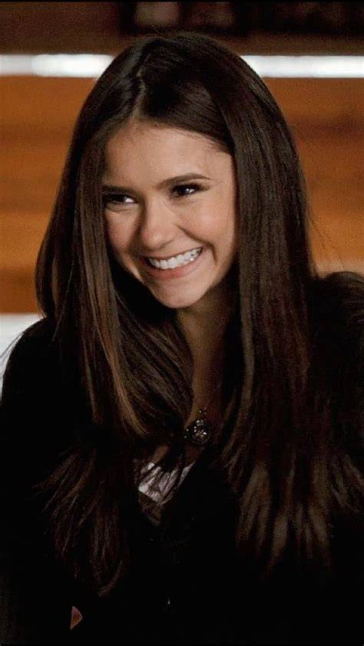 Elena Gilbert smiling at the camera in the woods in Vampire Diaries