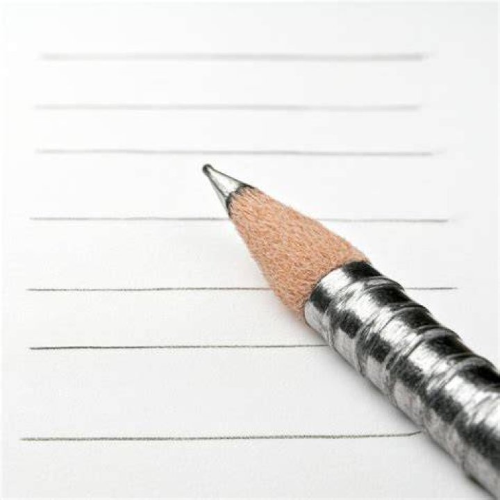lined notebook with sharpened pencil, pencil sharpener, and pencil shavings