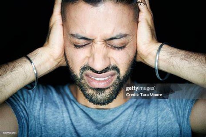 man blocking ears looking stressed