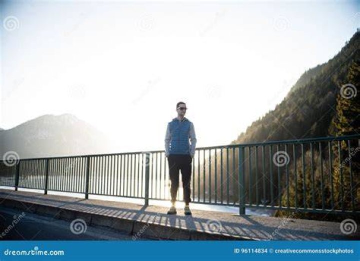 Man standing on a bridge near the mountains