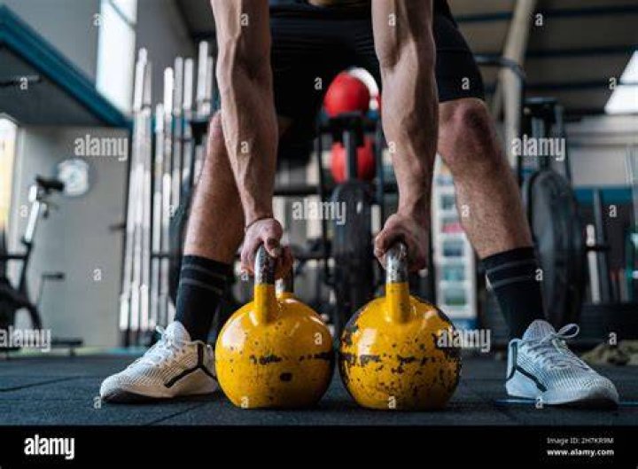 Muscular male athlete holding kettlebells in gym muscular male athlete holding kettlebells in gym