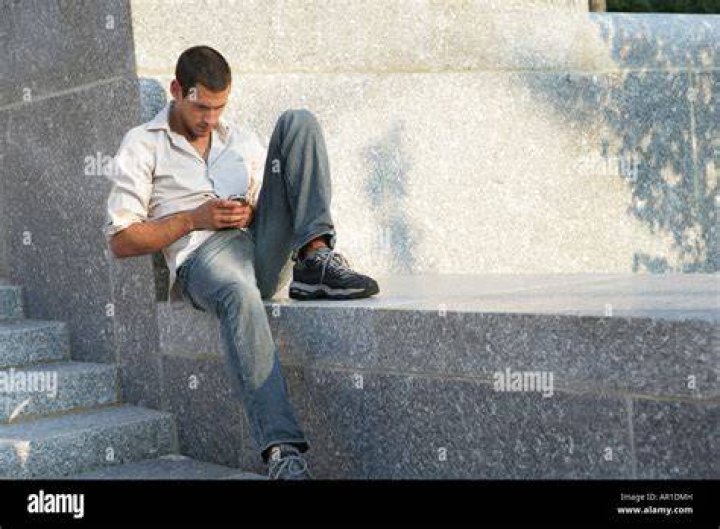 Person sitting on a ledge, overlooking a city