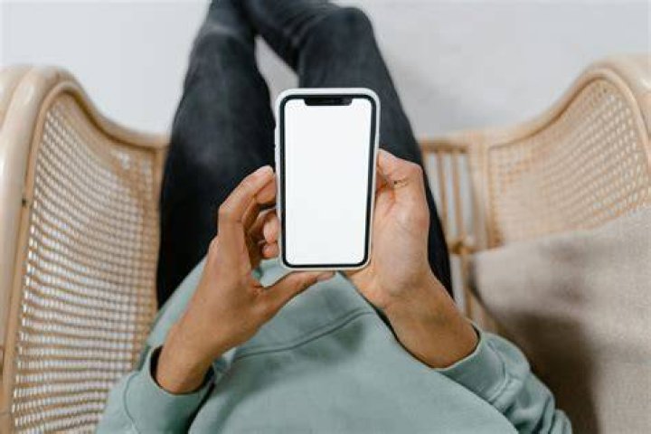person using phone in front of laptop