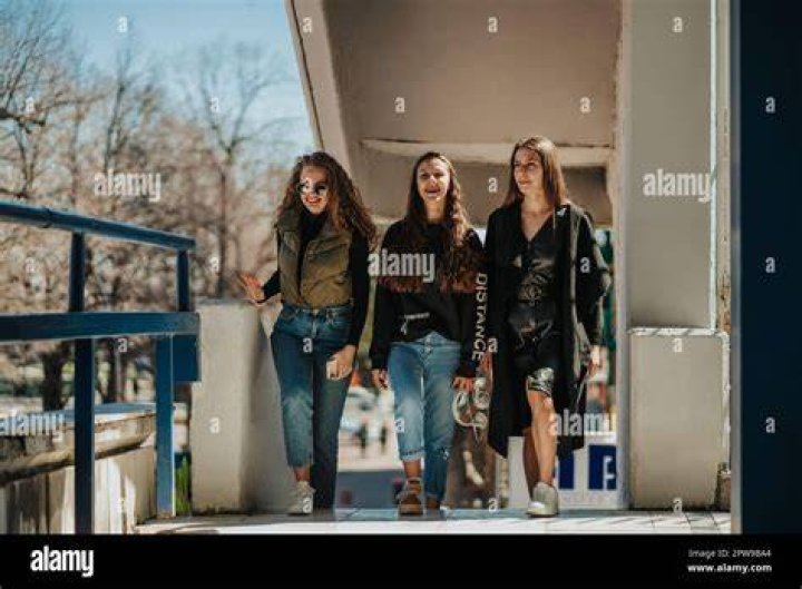 three girls smiling and walking down the street