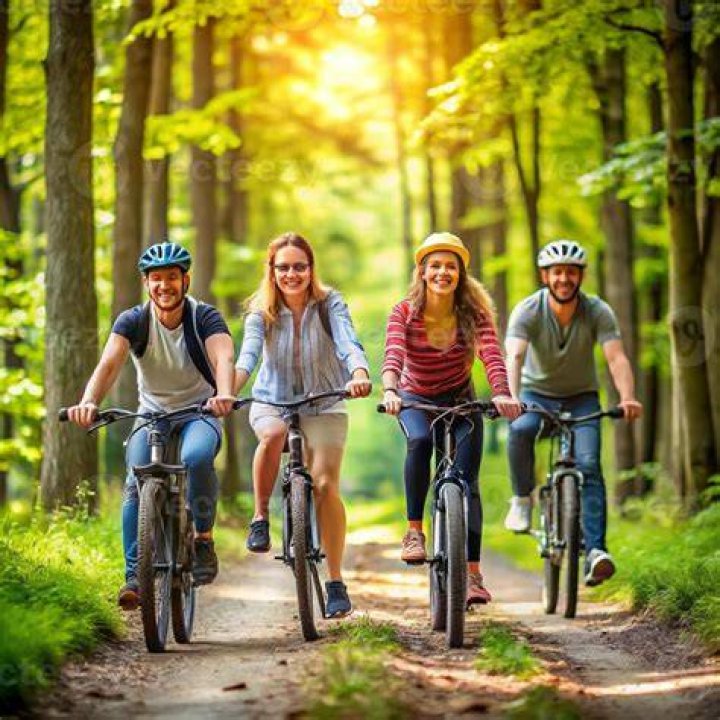 three people on bicycles in front of water and colorful buildings