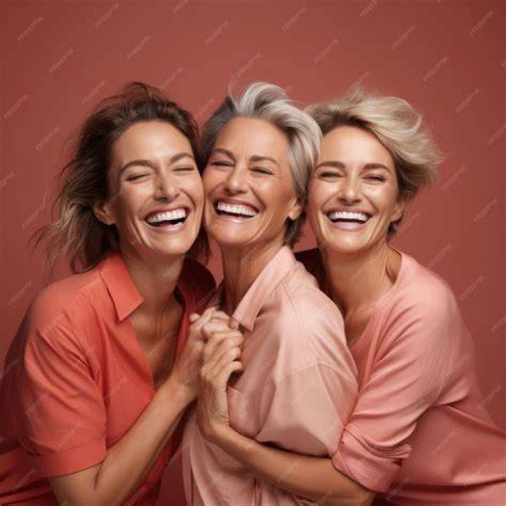 Three women standing beside a grey metal fence Three women standing beside a grey metal fence