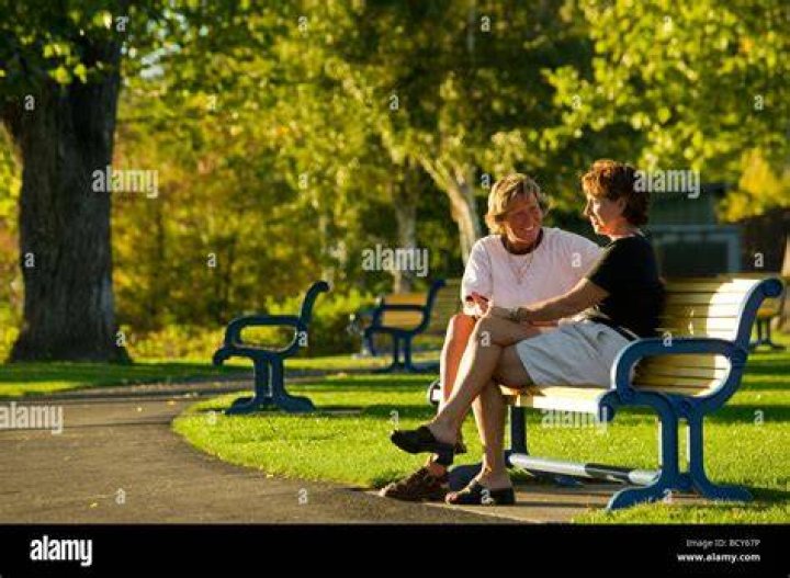 two people sitting in green grass with buildings in the background